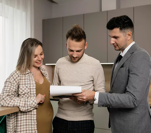 A man and a woman are reviewing documents with another man in a modern office space.